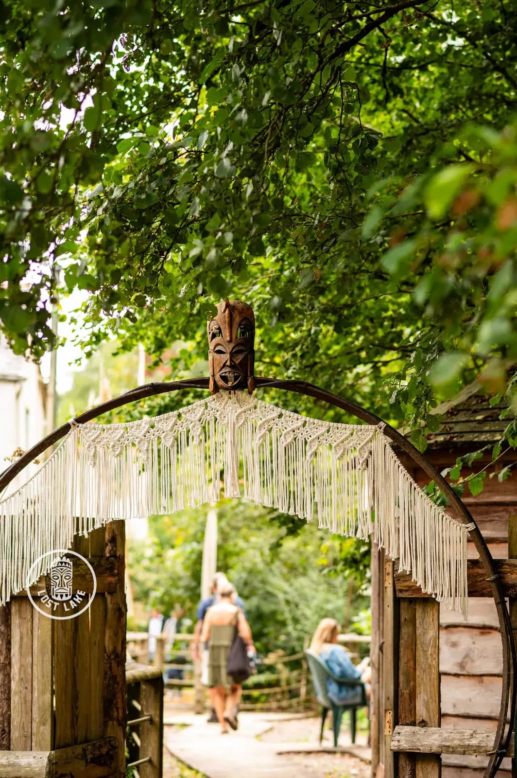 Looking through the Lost Lake gate, carved mask and macramé, into the site