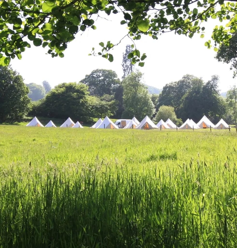 Riverside bell tents under open skies, North Devon countryside